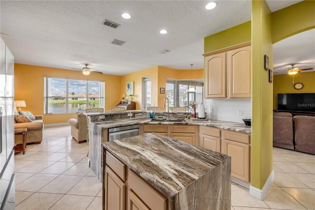 kitchen with ceiling fan, light brown cabinets, visible vents, and open floor plan