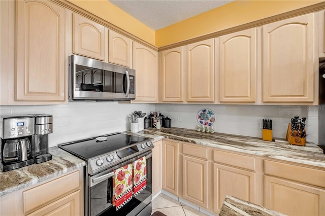 kitchen with a textured ceiling, light tile patterned floors, stainless steel appliances, light brown cabinetry, and tasteful backsplash