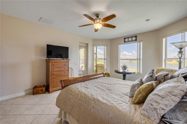 bedroom featuring visible vents, a textured ceiling, baseboards, and light tile patterned floors