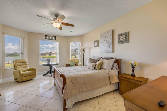 bedroom featuring light tile patterned floors, a textured ceiling, baseboards, and a ceiling fan