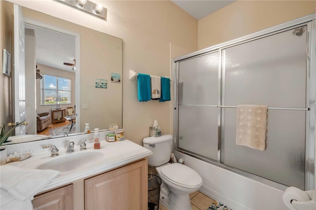 bathroom with combined bath / shower with glass door, vanity, and toilet