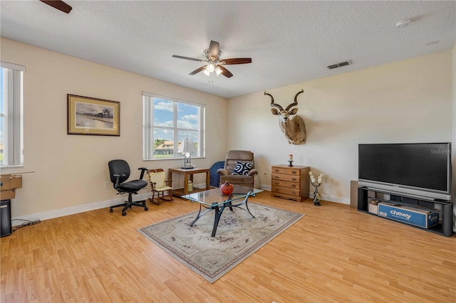 living area featuring light wood-style flooring, visible vents, and ceiling fan