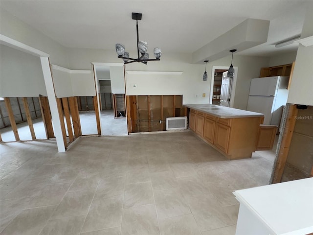 interior space featuring decorative light fixtures, a notable chandelier, light countertops, visible vents, and freestanding refrigerator