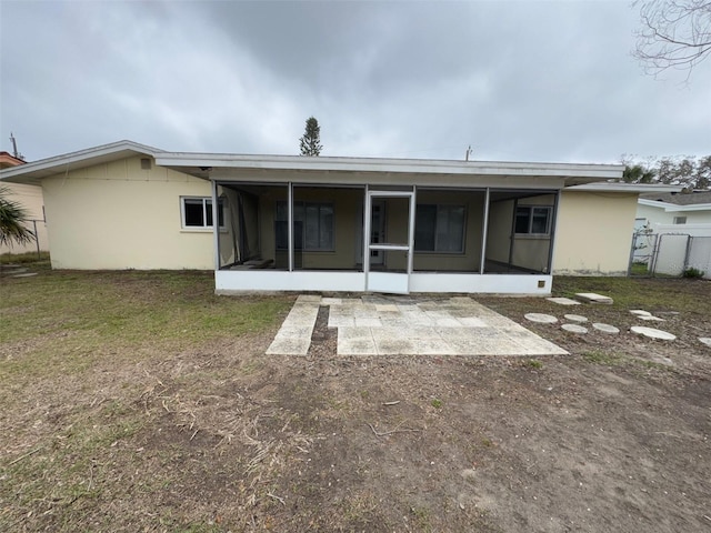 rear view of house with a yard, a sunroom, and fence