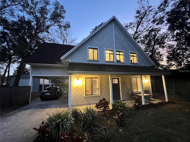 rear view of property featuring driveway, an attached carport, and a porch