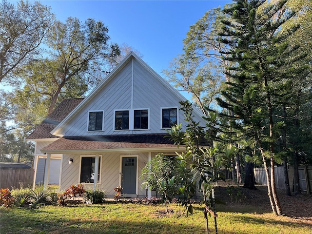 view of front of home with a porch, fence, a front yard, and a shingled roof