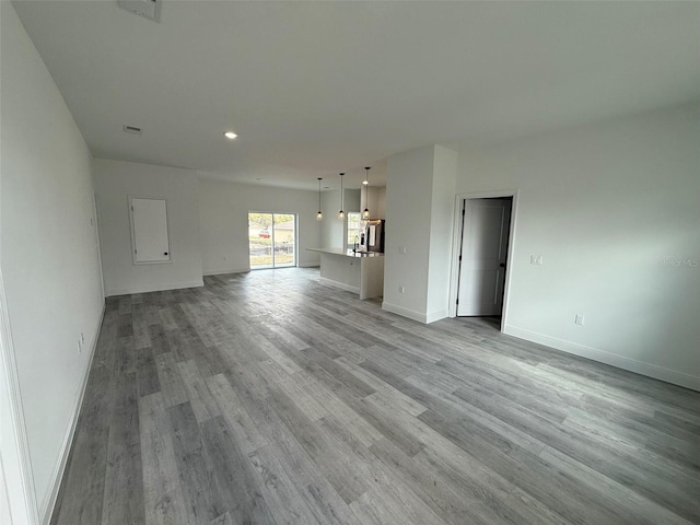 unfurnished living room featuring light wood-type flooring, visible vents, and baseboards