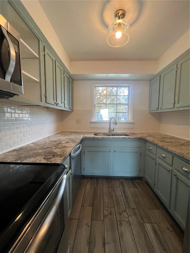 kitchen with light stone counters, appliances with stainless steel finishes, dark wood-style flooring, open shelves, and a sink