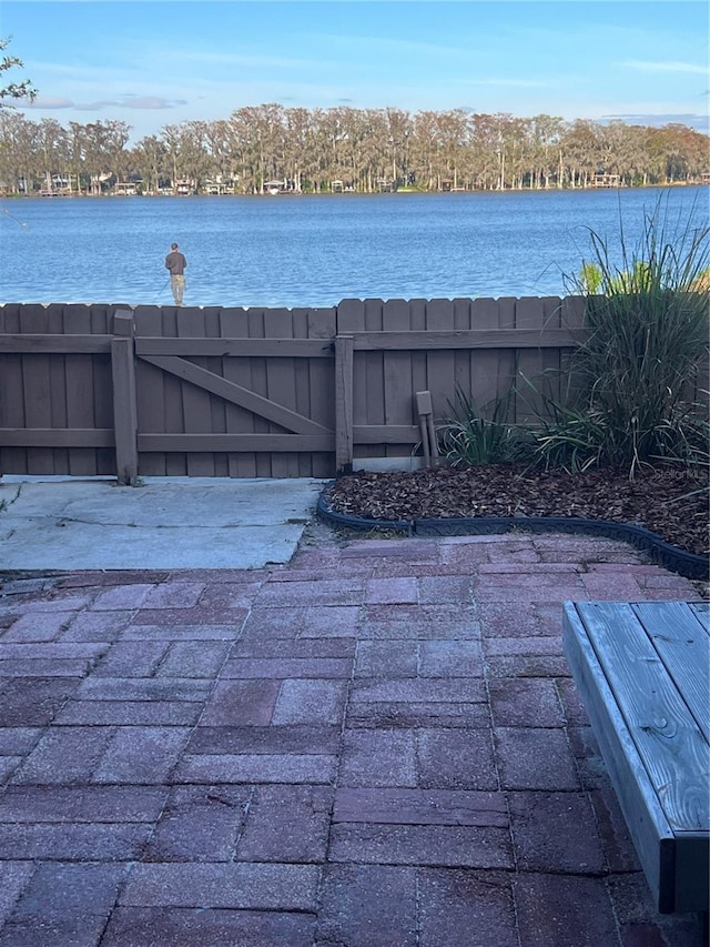 view of patio / terrace featuring a gate, a water view, and fence