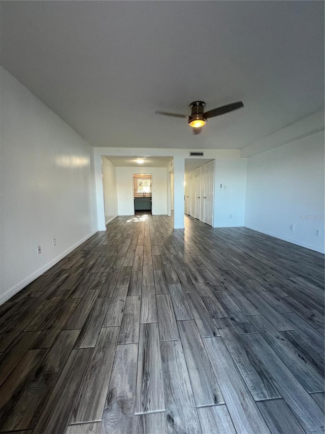 unfurnished living room with a ceiling fan, visible vents, baseboards, and wood finished floors