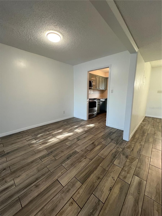 spare room featuring a textured ceiling, wood finish floors, and baseboards