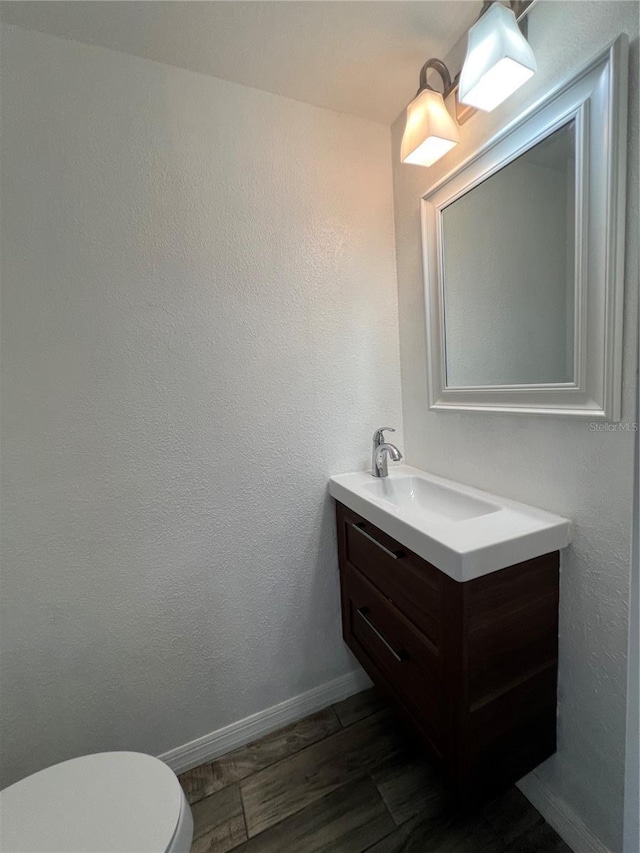 bathroom featuring toilet, wood finished floors, vanity, and baseboards