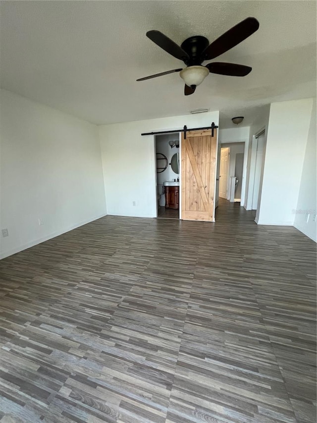 interior space featuring ceiling fan, a barn door, and a textured ceiling