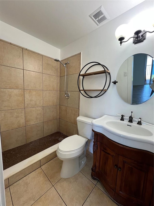 bathroom featuring tile patterned flooring, toilet, vanity, visible vents, and tiled shower