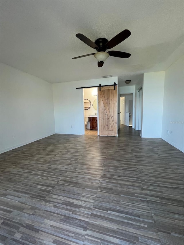 empty room featuring visible vents, ceiling fan, a textured ceiling, and a barn door