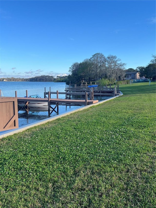 view of dock with a water view and a yard