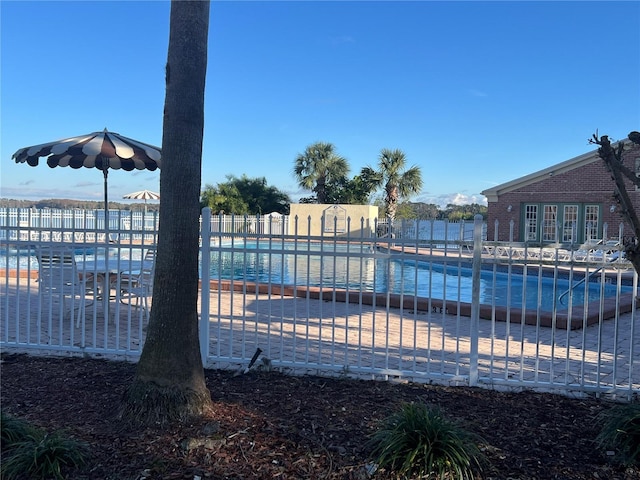 community pool with a water view and fence