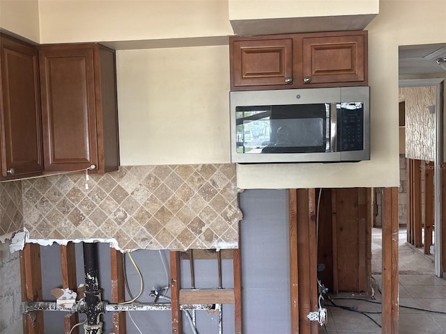 kitchen featuring tile patterned flooring, stainless steel microwave, and backsplash