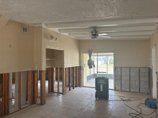 spare room with a ceiling fan, visible vents, beamed ceiling, and a textured wall