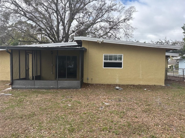 back of house with a sunroom, fence, and stucco siding