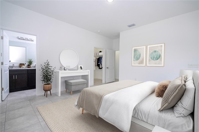 bedroom with a spacious closet, light tile patterned floors, visible vents, and ensuite bathroom