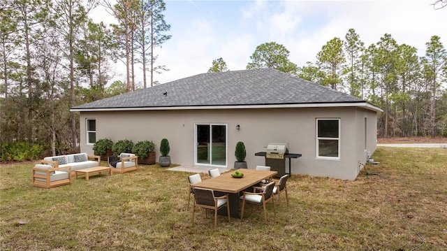 back of property featuring a shingled roof, stucco siding, a lawn, and an outdoor hangout area