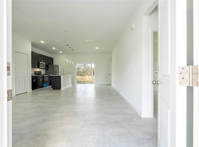 unfurnished living room featuring recessed lighting, baseboards, light tile patterned floors, and a sink