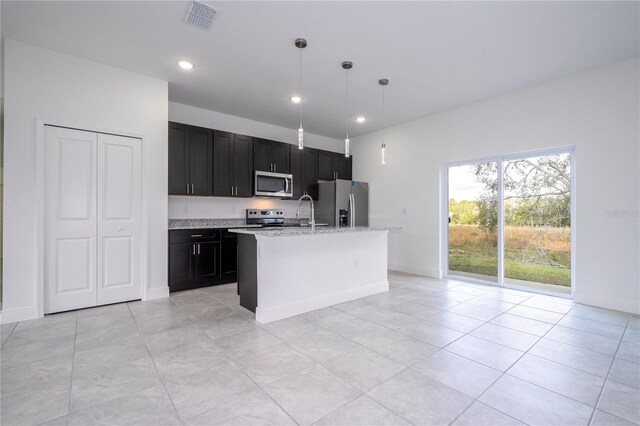 kitchen featuring a center island with sink, visible vents, stainless steel appliances, pendant lighting, and dark cabinets