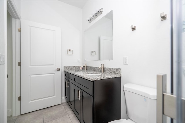 bathroom with a sink, toilet, double vanity, and tile patterned flooring