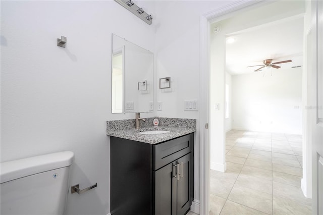 bathroom with tile patterned flooring, baseboards, ceiling fan, toilet, and vanity