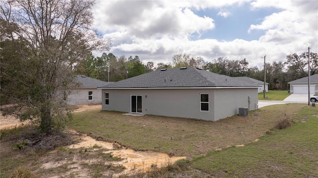 back of property with a yard, roof with shingles, central AC, and stucco siding