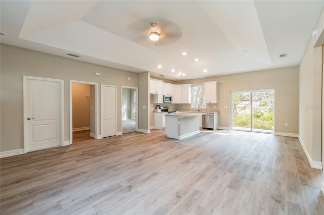 kitchen with white cabinets, open floor plan, light countertops, appliances with stainless steel finishes, and a center island