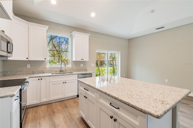 kitchen featuring a center island, visible vents, appliances with stainless steel finishes, white cabinetry, and a sink