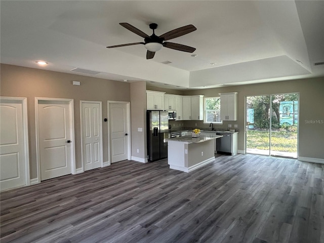 kitchen with dark wood-style flooring, appliances with stainless steel finishes, white cabinetry, a kitchen island, and a sink