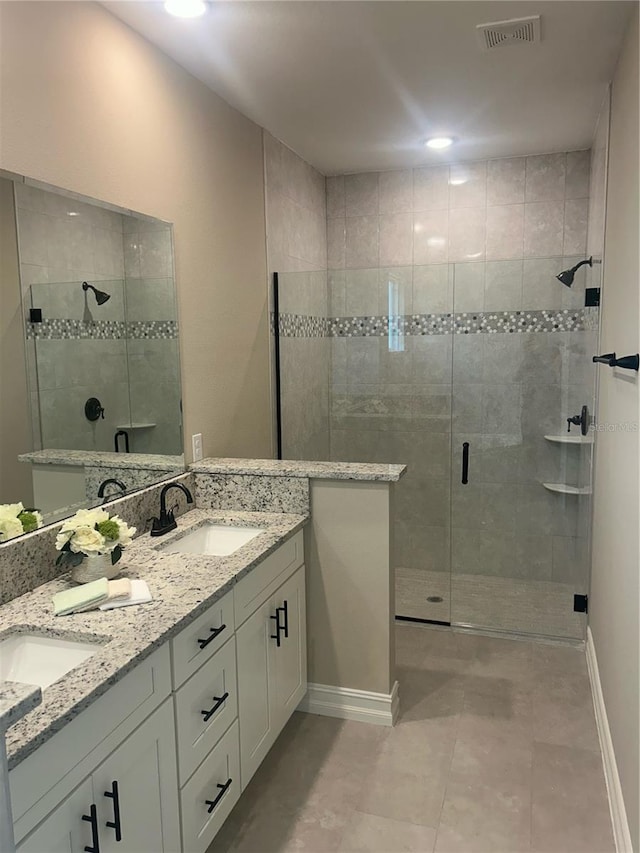 full bathroom with double vanity, a stall shower, visible vents, and a sink