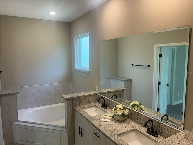 bathroom featuring a sink, a bath, and double vanity