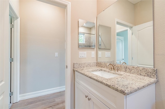 bathroom with wood finished floors, vanity, and baseboards