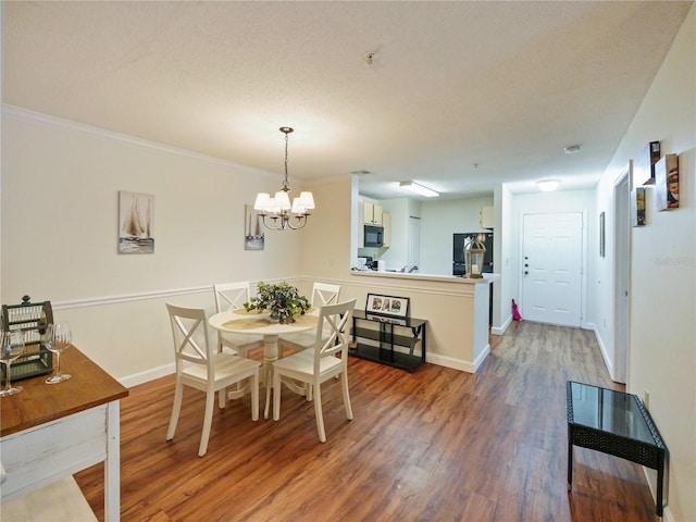 dining room featuring an inviting chandelier, crown molding, baseboards, and wood finished floors