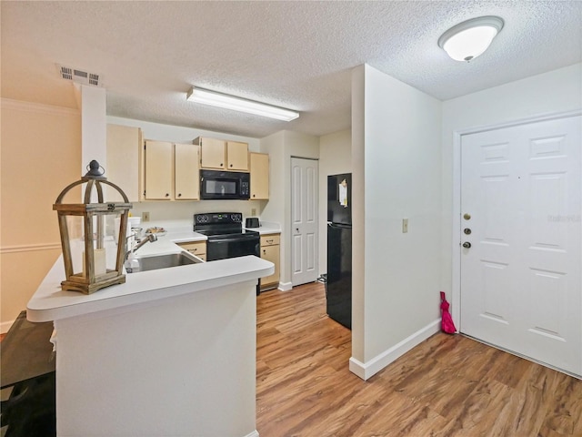 kitchen featuring visible vents, light wood-style flooring, light countertops, black appliances, and a sink