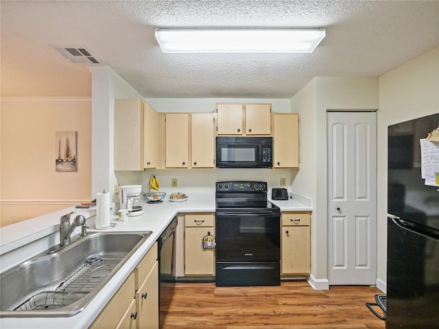 kitchen featuring black appliances, light wood-style flooring, visible vents, and a sink