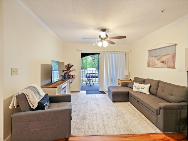 living area with ceiling fan, a textured ceiling, crown molding, and wood finished floors