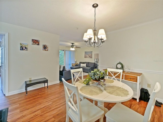 dining space with crown molding, light wood-style flooring, baseboards, and ceiling fan with notable chandelier