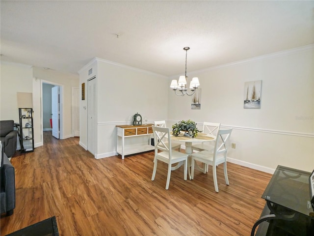 dining space featuring light wood-style floors, crown molding, baseboards, and an inviting chandelier