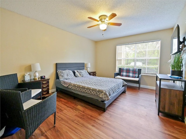 bedroom with a textured ceiling, ceiling fan, wood finished floors, and baseboards