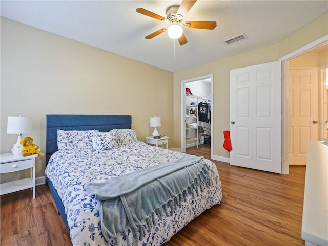 bedroom featuring a closet, a spacious closet, visible vents, and wood finished floors