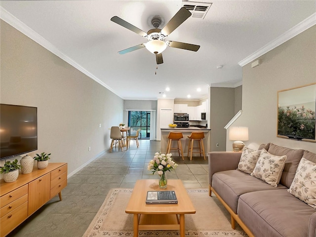 living area featuring light tile patterned floors, visible vents, baseboards, a ceiling fan, and ornamental molding