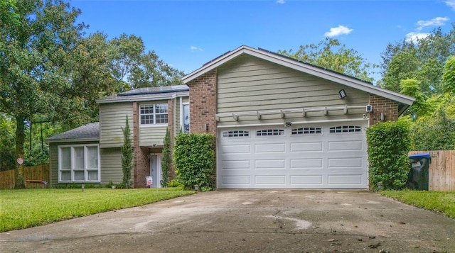 view of front of home featuring a front yard, brick siding, fence, and driveway