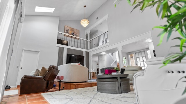 living area featuring a skylight, light tile patterned floors, a high ceiling, and stairs