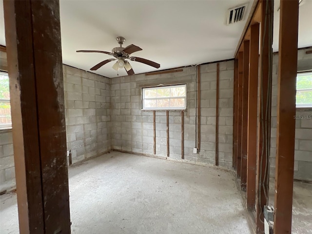 basement with ceiling fan, visible vents, and concrete block wall