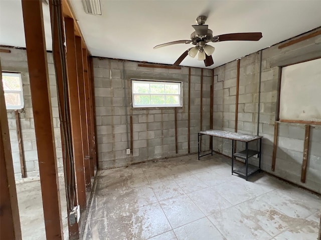 interior space featuring concrete block wall, visible vents, and ceiling fan